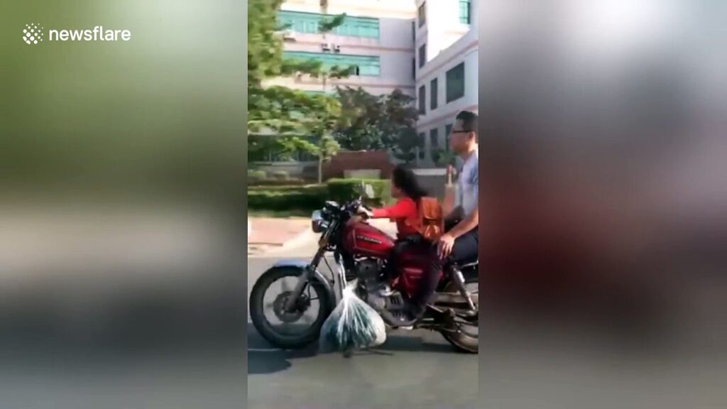 La niña conduce la motocicleta de su padre en una carretera en China
