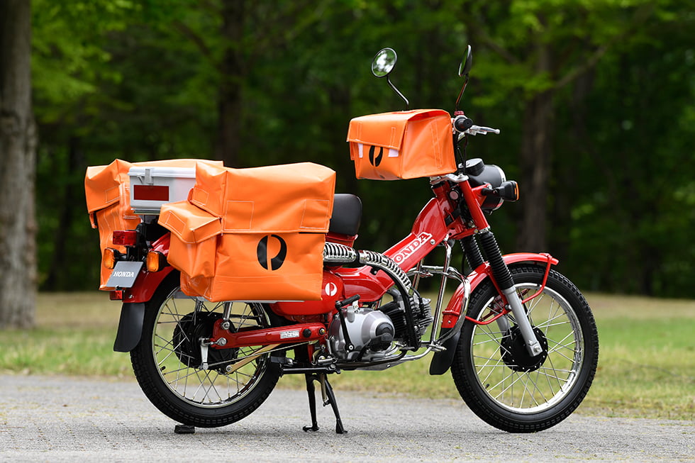 Una bicicleta Honda CT110 'Postie' con bolsas de correo en un parque
